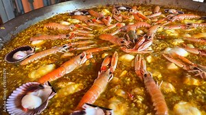 Cooking a big traditional Spanish seafood Paella dish with shrimps, St Jacques scallops and Cigala Norway lobsters Nephrops norvegicus, cooked rice with seafood, Marbella Spain, 4K shot Stock Video