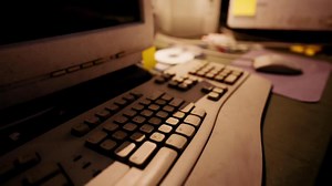 A close up view of an old computer keyboard and monitor setup in an office