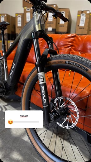 We’re chillin’ at the CyclErie Warehouse and can’t get over how stoked we are on this Aventon Ramblas eMTB! 🔥 The Gold Wolf Tooth Components add that perfect touch of bling, shining bright on the drivetrain, while those tan-wall Teravail Honcho tires bring rugged style and singletrack-ready grip. Paired with a slick RockShox fork and hydraulic disc brakes, this beast is built for the trails—and looks damn good doing it. Set against a vibey red leather couch with boxes of Ramblas goodies stacked