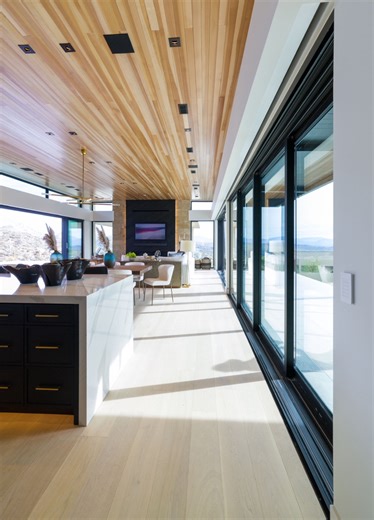 This great room is the heart of a Netzero home where design, performance, and the surrounding landscape all work in harmony. This is Netzeroass invites the desert views in while flooding the space with natural light, reducing the need for artificial lighting throughout the day. High-performance glazing, deep overhangs, and precision building science allow this home to operate at peak efficiency without compromising the modern aesthetic. Warm wood ceilings, expansive multi-sliders, and clean arch