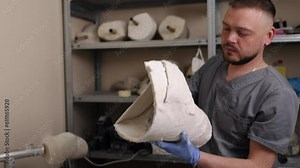 Crafting techniques, Leg modeling, Plaster modeling. Man in professional workspace constructing plaster model of prosthetic leg for hip disarticulation.