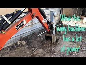 Mini backhoe digging up a sewer pipe