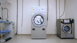 Industrial laundry room. Washer machines in laundry service. Industrial laundry machine washing clothes. Hotel laundry room. Industrial washer and dryer working