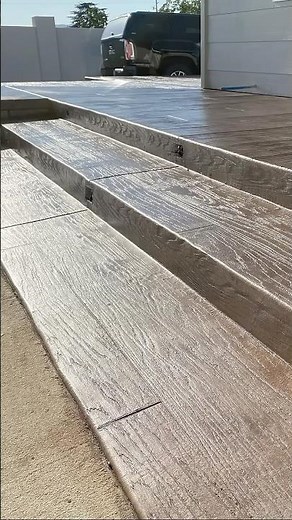 Raised patio with wood plank stamped concrete, cantilever edges and lights installed in the steps.