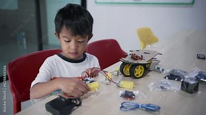 Kindergarten asian student learn in coding robot car and electronic board cable in STEM Arduino, Computer code in robotics for kids.