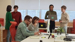 Handsome database developer pointing pencil at computer screen with software compiling code explaining source algorithm to young female coworker. System engineers discussing ai team project.