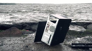 Man breaks a computer with a sledgehammer. A man destroys a computer on the street. The concept of the dangers of technology