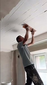 Applying plaster to a cracked ceiling surface using a hand trowel