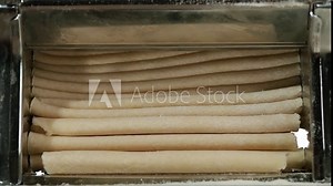 Traditional italian homemade pasta being made on machine for cutting dough. Fresh spaghetti pasta coming out of pasta machine, close-up. Chef use pasta cutting machine