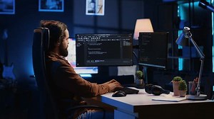Experienced programmer writing code on computer screen while in office using java programming languages. Developer working on fixing database errors while working from home, camera A