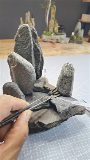 Daily Vibes Of Artist on Instagram: "A quiet mountain world, built stone by stone 🌿 This miniature landscape is handcrafted from natural rock, layered with patience and intention. Tall weathered peaks rise from a grounded base, connected by worn steps and soft paths of moss. Subtle details invite the eye to wander and slow down, like a pause in time where nature and imagination meet 🪨 Each piece is composed by hand, balancing weight, texture, and negative space to capture the feeling of a vast