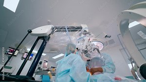 Neurosurgical procedure in operating room. Surgeon and assistant perform a neurosurgery through the modern microscope.